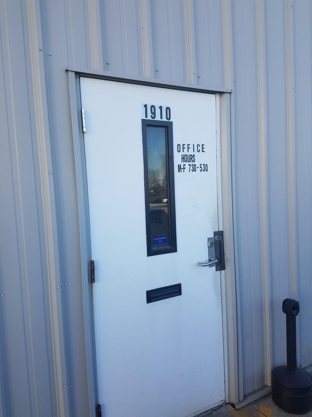 The office door marked 1910 with office hours Monday to Friday 7:30 to 5:30 painted on it