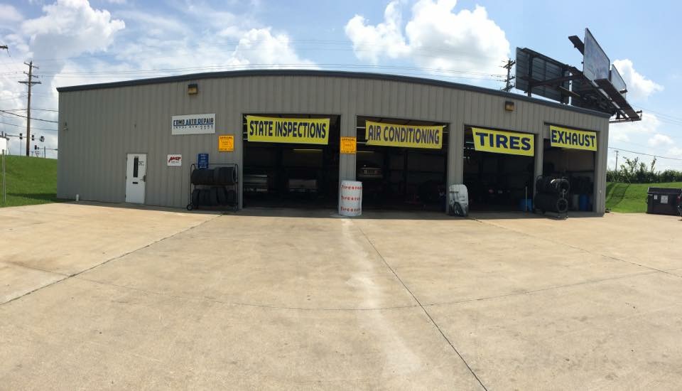 The front of the shop with the bay doors open and banners reading state inspections, air conditioning, tires and exhaust